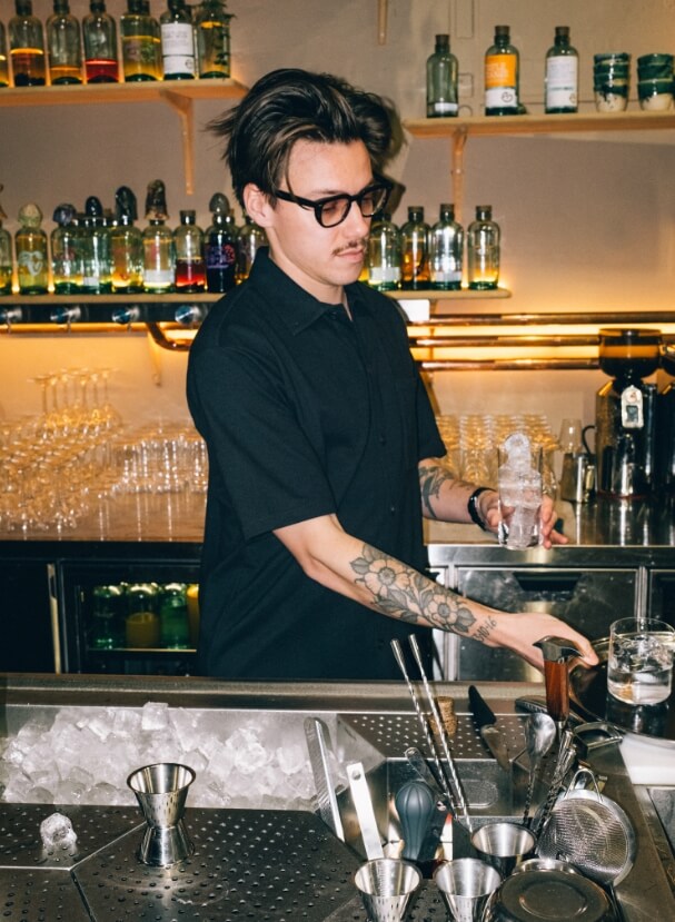 Bartender placerar is i ett glas bakom välutrustad bardisk.